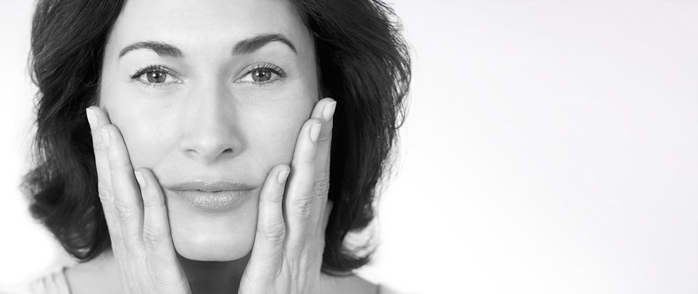 Femme d'âge mûr se touchant les joues avec les deux mains.