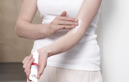 Femme appliquant EUCERIN AtopiControl Crème Calmante Intensive dans le pli du coude.