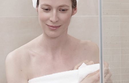 Femme après la douche, enroulée dans une serviette, une serviette en turban sur la tête.