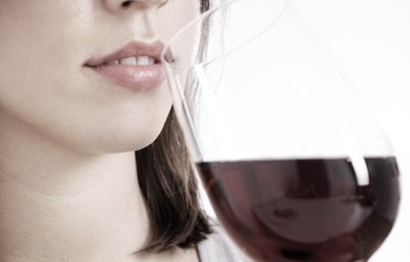 Femme buvant un verre de vin rouge.