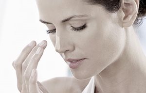 Femme appliquant un écran solaire sur son nez.