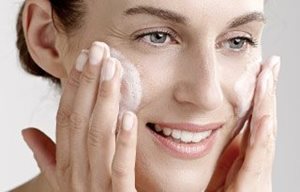 Woman applies cleansing gel on her face.
