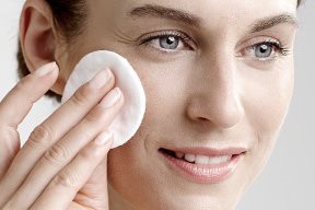 Woman applies toner with cotton pad.