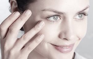 Une femme applique le soin sur sa joue