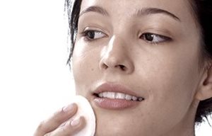 Femme appliquant la lotion tonique sur son visage avec un coton à démaquiller