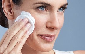 Une femme applique EUCERIN DermatoCLEAN Lait Démaquillant Doux.