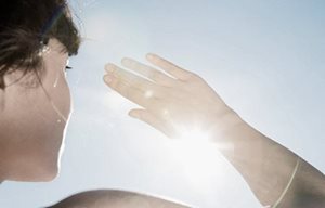 Femme se protégeant les yeux du soleil avec la main droite.