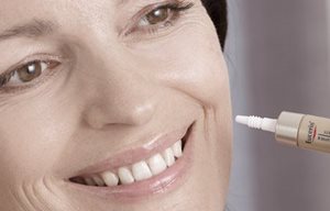 Femme appliquant un produit Eucerin sur sa joue gauche.