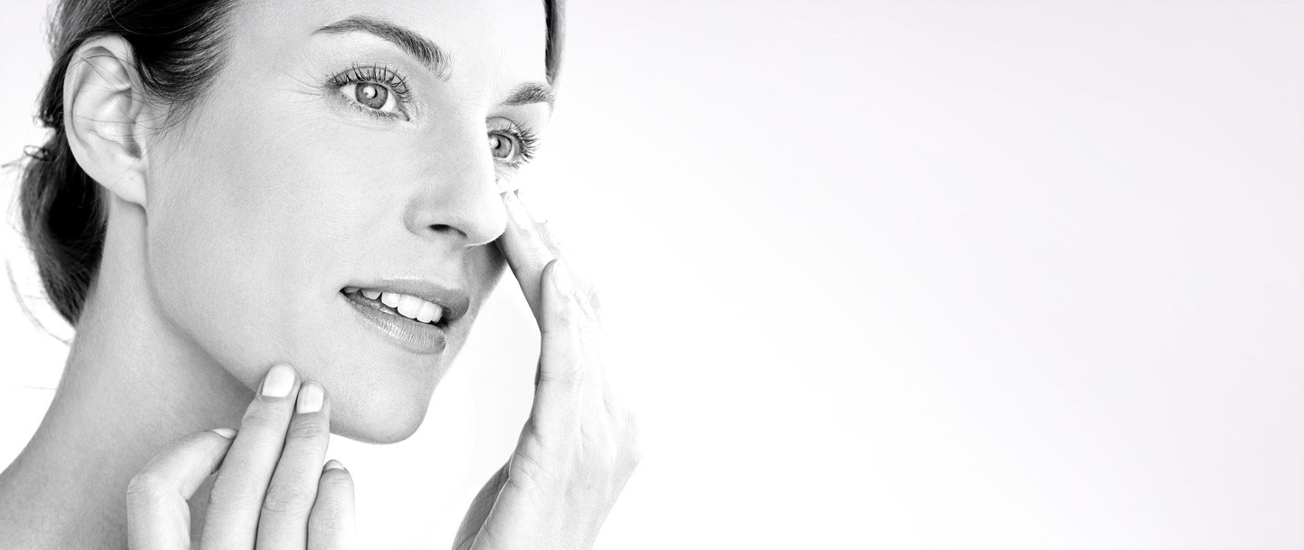 Femme appliquant de la crème sur sa joue.