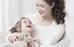 Mère portant son enfant dans ses bras, l'enfant porte un animal en peluche.