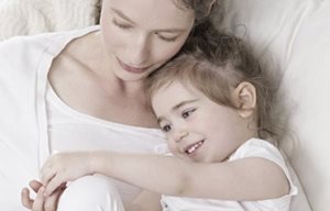 Mère et enfant assis côte à côte qui se font des câlins.