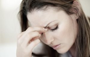 Femme au regard baissé, air stressé - sa main touche son front