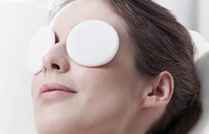 Femme qui se détend avec des compresses sur les deux yeux.